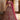 Woman in a traditional embroidered outfit standing in an elegant interior setting.